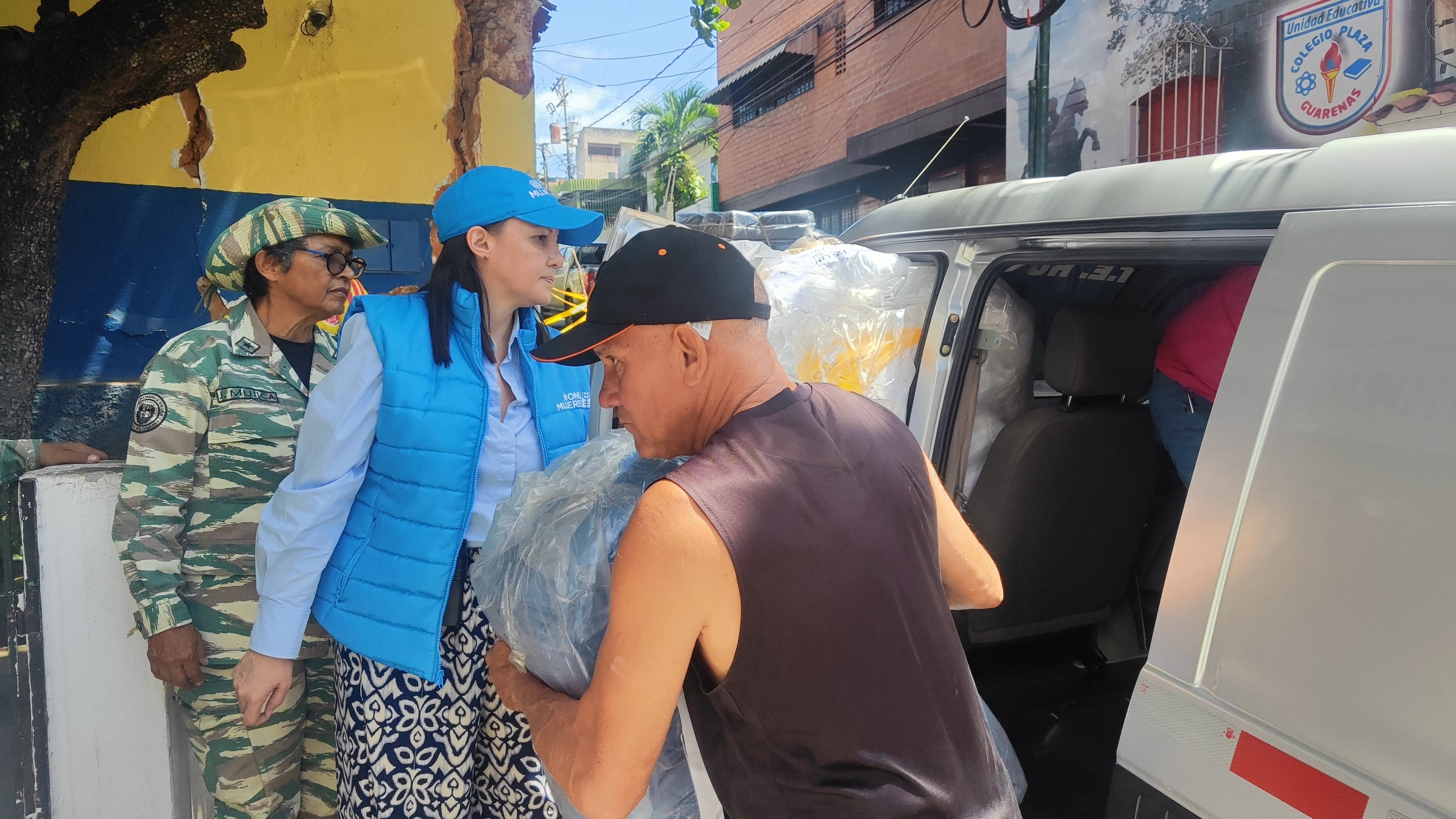 goods unloading from van as woman in UN Women vest watches