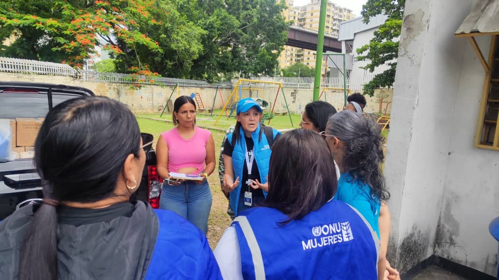 women in UN Women vest addressing group next to a pick up truck